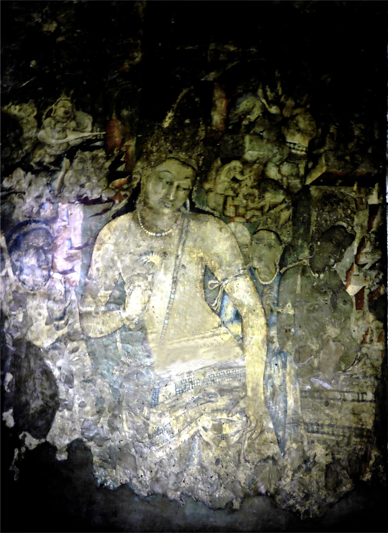 Karanlık mağara içinde lotus tutan mücevherli bodhisattva Padmapani ve çevresinde küçük eşlikçileri gösteren aşınmış duvar resmi.