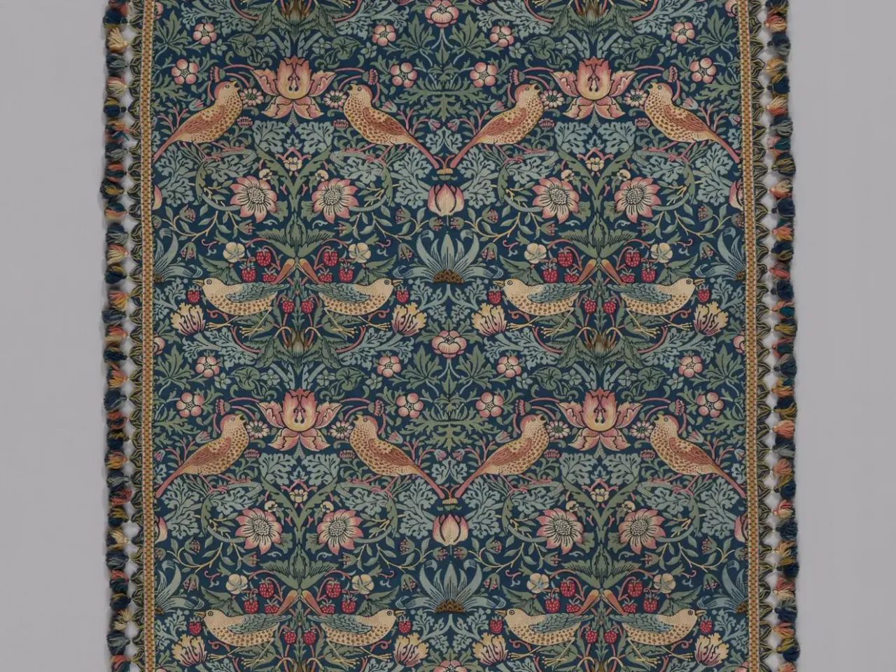 Birds face each other among repeated strawberries, flowers and curling stems in a detail of Morris’s printed textile