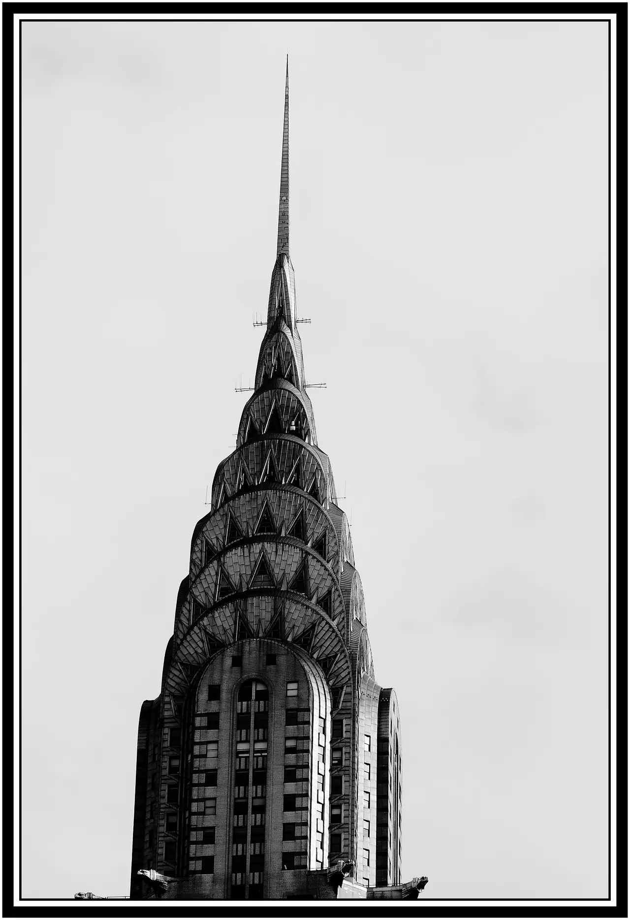 A monochrome photograph shows the Chrysler Building’s upper tower, layered steel arches, triangular windows and tall spire