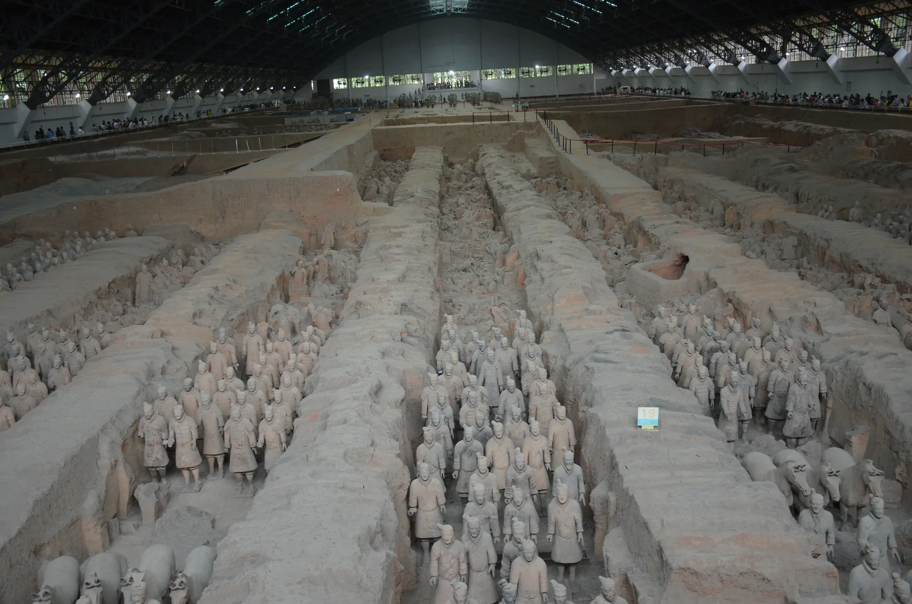 Xi'an yakınındaki 1 numaralı çukurun modern koruyucu salonunda uzun toprak koridorlarda duran gerçek boyutlu pişmiş toprak asker ve at sıraları.