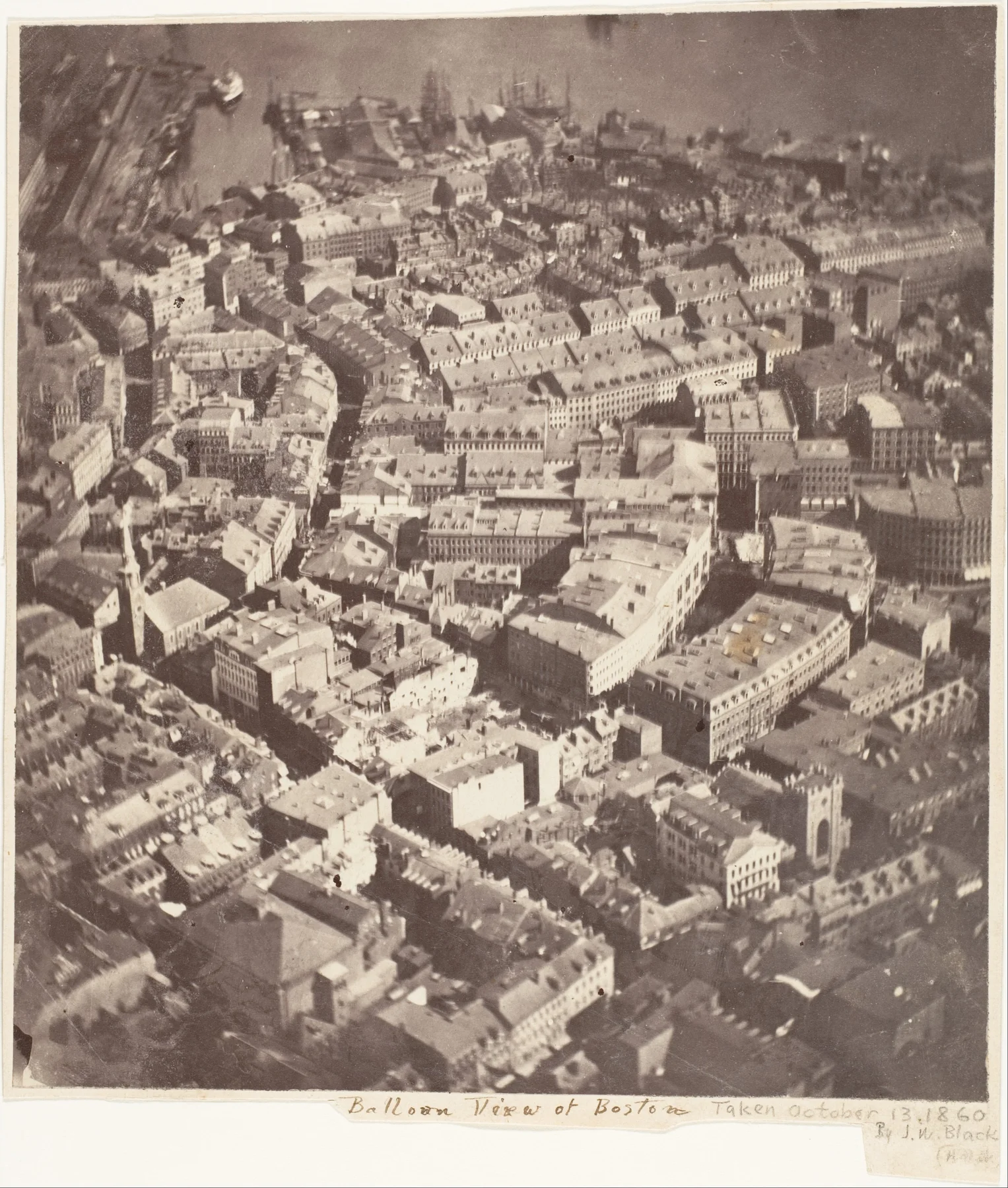 Yoğun on dokuzuncu yüzyıl Boston yapıları, sokakları, çatıları ve kilise kulelerine dik açıyla bakan sepya hava fotoğrafı; baskının altında elle yazılmış balon görünümü etiketi.