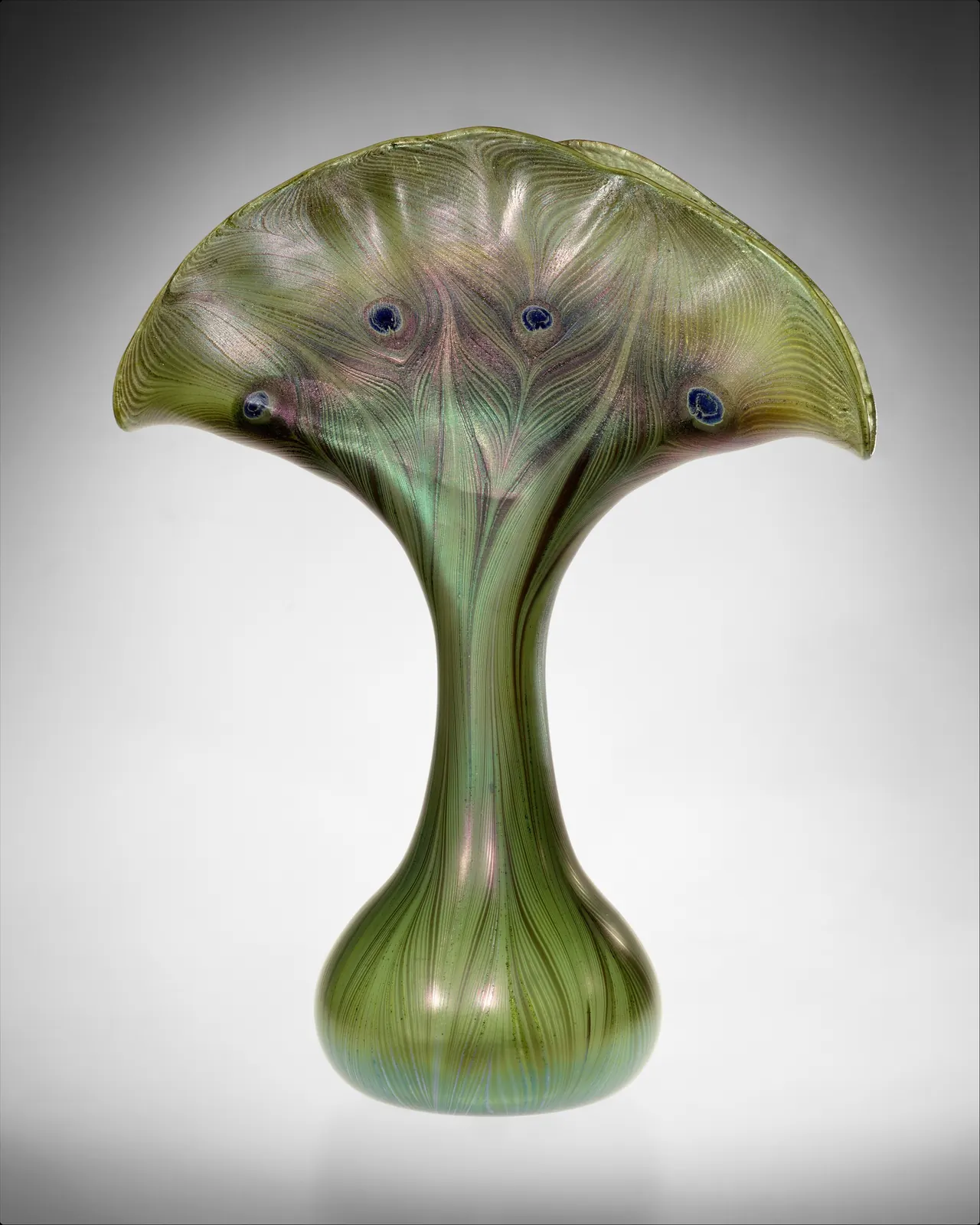 Tiffany’s green glass vase opens into a broad fan with blue eye-like feather markings above a narrow stem