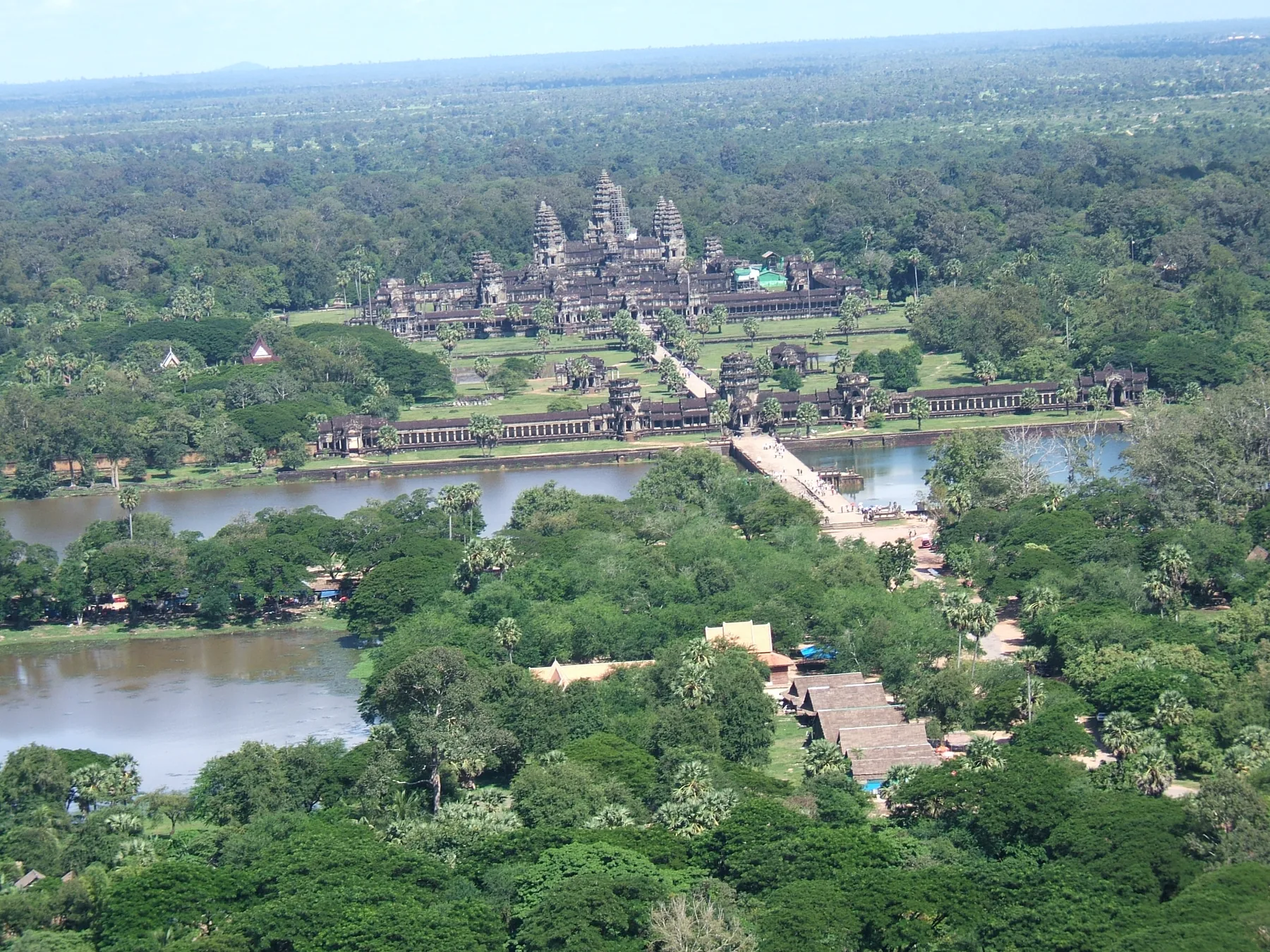 Havadan görünüm, Angkor Wat’ın uzun geçidi, geniş hendeği, dış çevre duvarı ve yoğun ağaçlıklı peyzaj içindeki beş kuleli merkezî tapınağı boyunca uzanır.