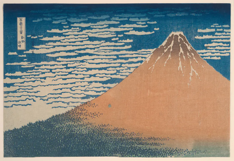 Mount Fuji rising red against a blue sky with small clouds in a print by Hokusai