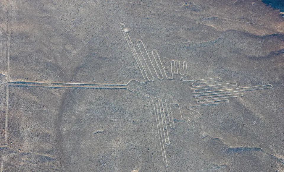 Havadan fotoğrafta Nasca çölünün koyu çakıllı yüzeyi üzerinde sinekkuşu jeoglifinin açık renk çizgileri.