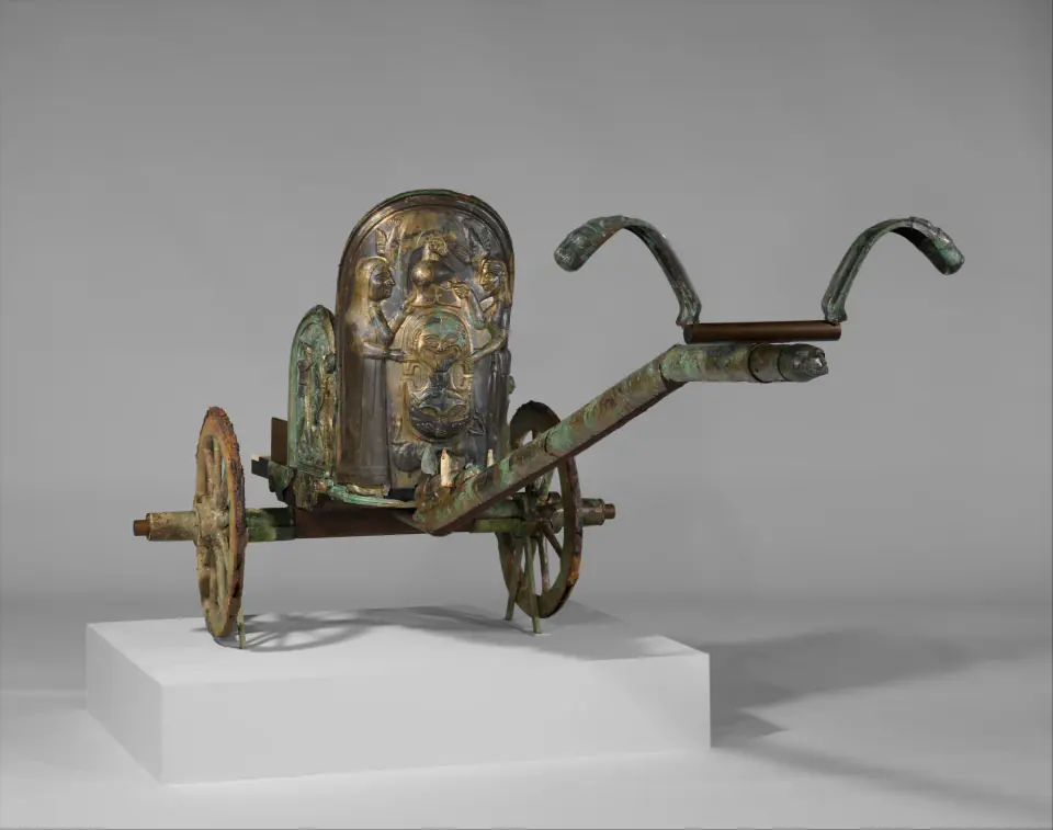 Kabartmalı bronz levhalarla kaplı, modern taşıyıcı üzerinde yeniden kurulmuş iki tekerlekli Etrüsk savaş arabası, nötr müze fonunda.